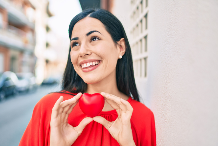 healthy latin women holding heart outside in a city. Concept for heart health.  