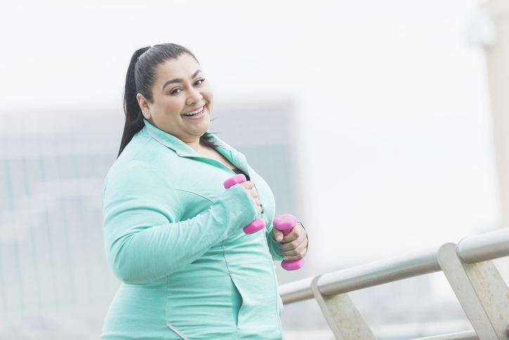 Overweight Hispanic women focused on weight loss in the New Year.  Jogging outside in winter with weights.