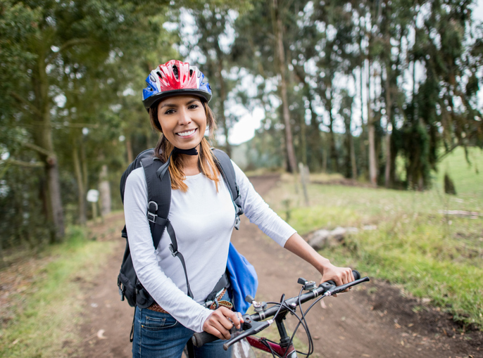Woman riding a bike in the North Georgia mountains and wearing light colored long sleeve clothing for tick prevention.