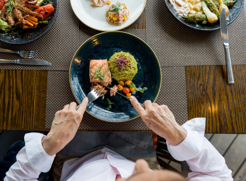 Close-up on a woman eating salmon for dinner at a restaurant - fish rich in omega 3 fatty acids 