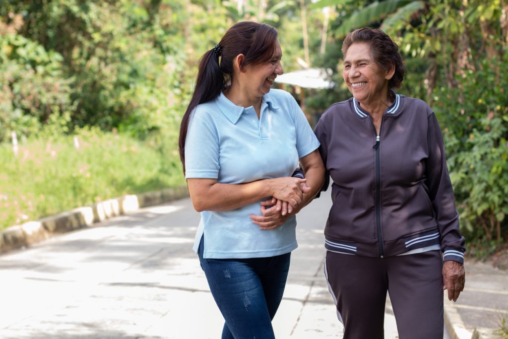 Adult woman supporting her elderly mother on a morning walk. Concept of active aging and low inflammation.