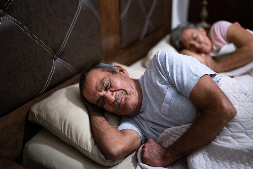 Senior man sleeping in the bedroom at home. recommended sleep helps prevent risk of heart attack, high blood pressure, obesity, and diabetes.   